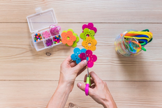 A person's hand cutting flower patch with scissor over the table