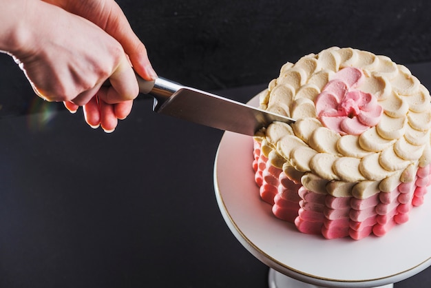 A person's hand cutting layer cake