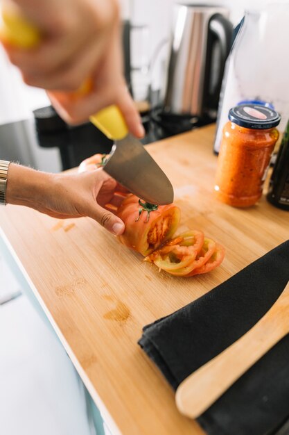 날카로운 칼로 토마토의 사람의 손 절단 조각