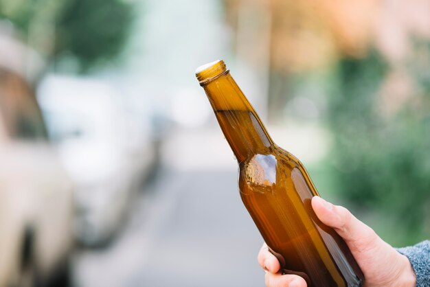 A person's hand holding beer bottle