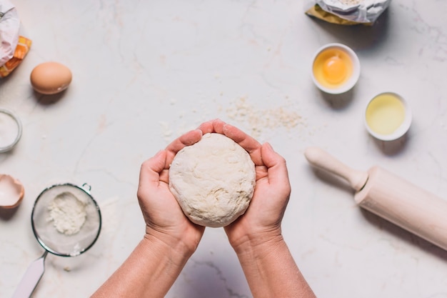 A person's hand holding dough with baking ingredients on kitchen counter