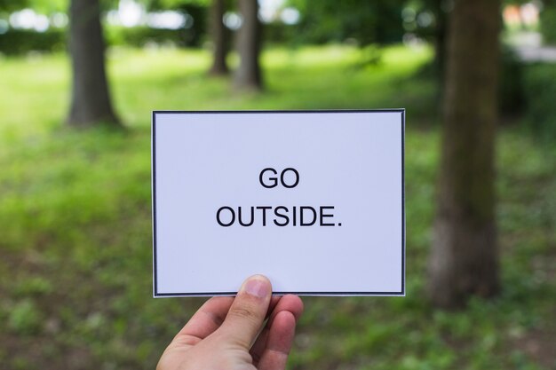 Person's hand holding placard with go outside text