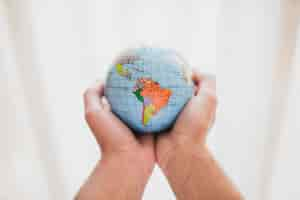 Free photo a person's hand holding small globe