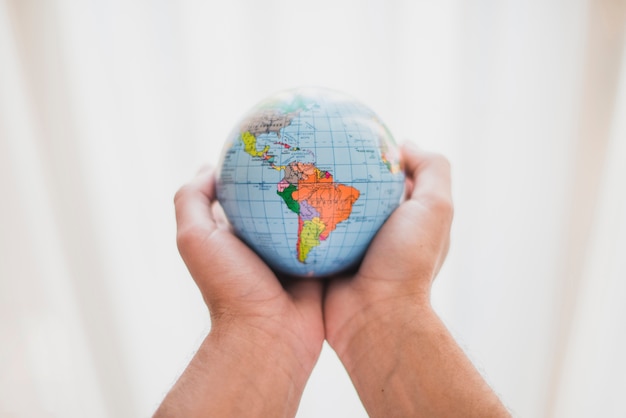 A person's hand holding small globe