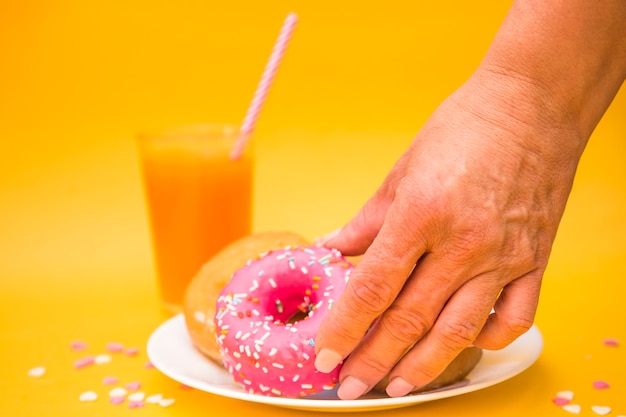 A person's hand picking up pink donut