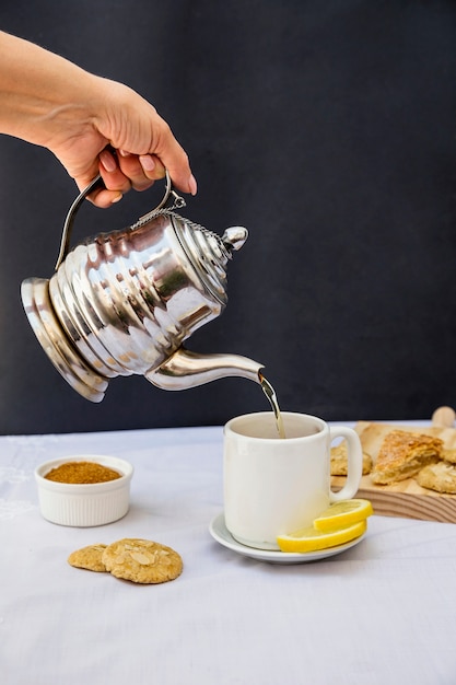 La mano di una persona che versa il tè in tazza