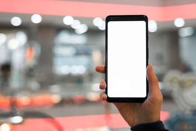 背景をぼかした写真に対して携帯電話の画面を示す人の手
