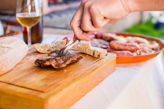 A person's hand slicing cooked meat on chopping board