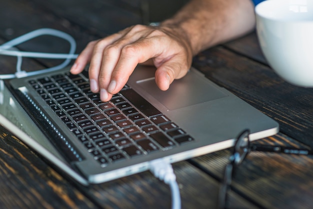 A person's hand typing on laptop keypad