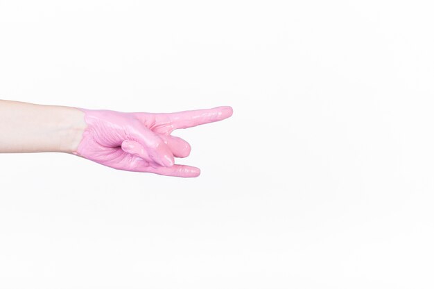 A person's hand with pink paint making horn sign