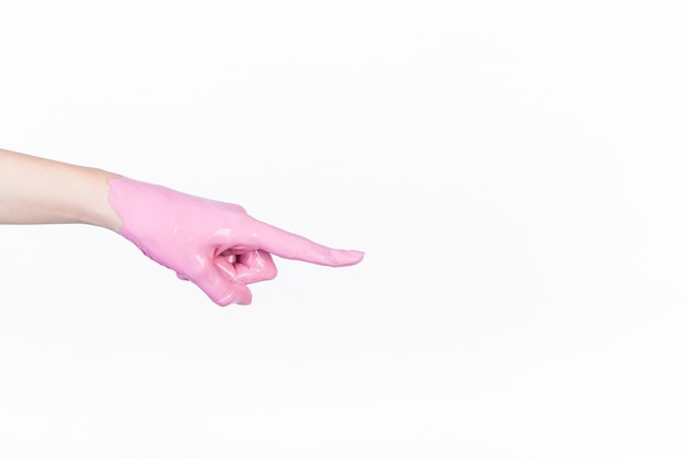 Person's hand with pink paint pointing finger on white background
