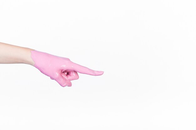 Person's hand with pink paint pointing finger on white background