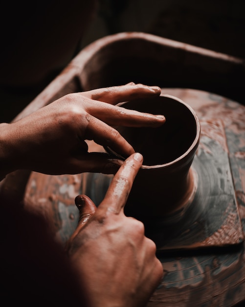 Руки и пальцы человека, создающие глиняный горшок