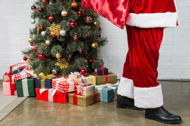 Persona in tuta di babbo natale vicino all'albero di natale