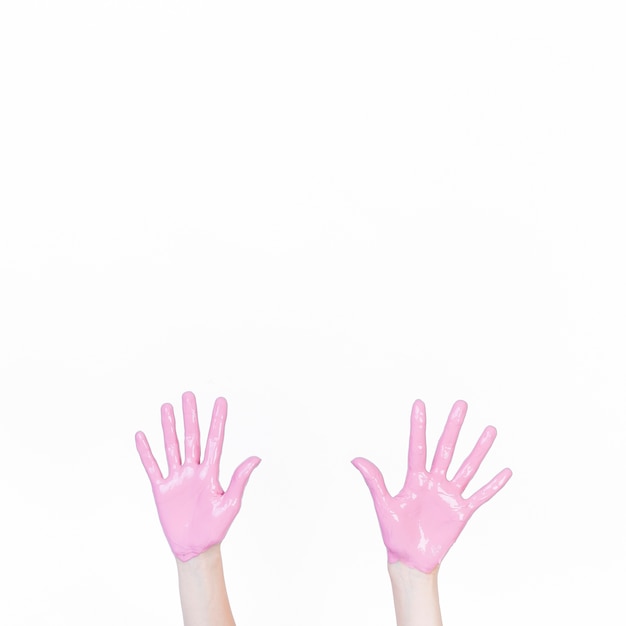 A person showing hand with pink paint against white background