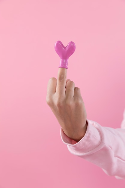 Человек показывает средний палец с воздушным шаром в форме сердца
