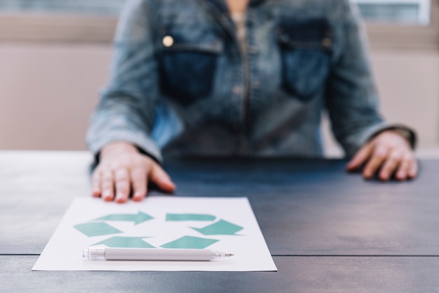 A person showing recycle paper with pen on wooden table