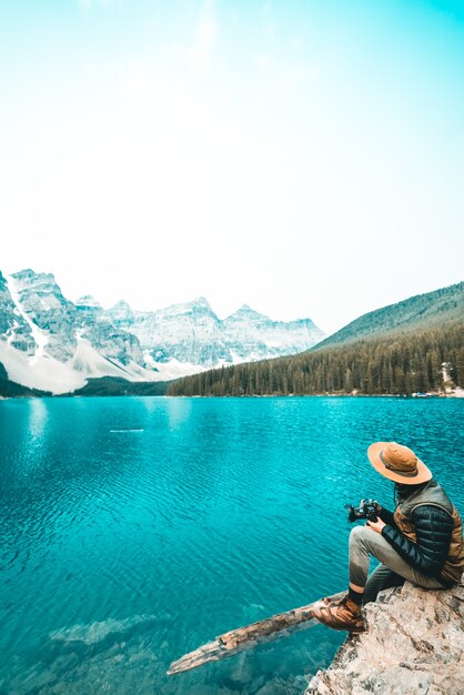 Person sitting on cliff near body of water