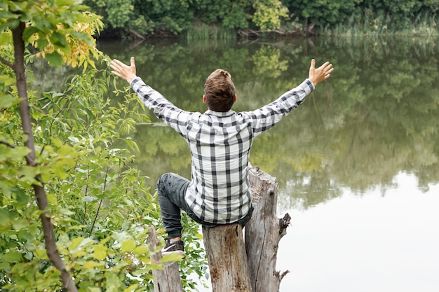 Бесплатное фото Человек, сидящий на дереве с широко открытыми руками