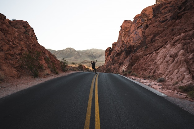 Free photo person skating on a highway road surrounded by red rocks