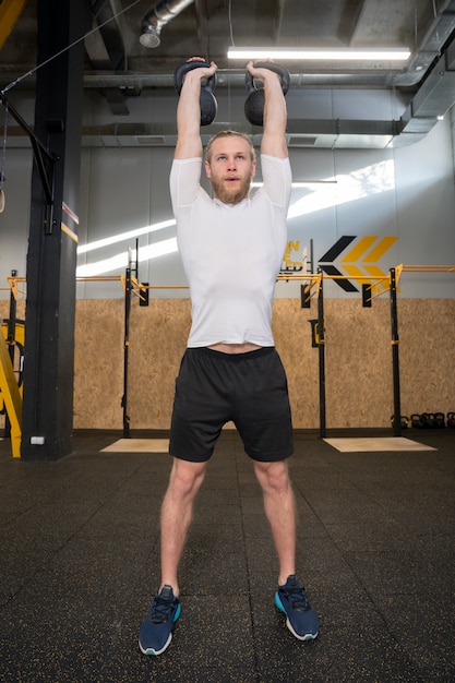 Free photo person in sport gym using kettlebells