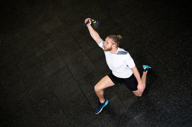 Free photo person in sport gym using kettlebells