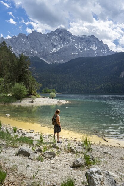 산으로 둘러싸인 독일의 Eibsee 호수 해변에 서있는 사람