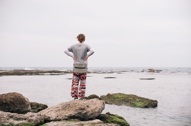 Free photo person standing on the mossy rocks on the body of the water