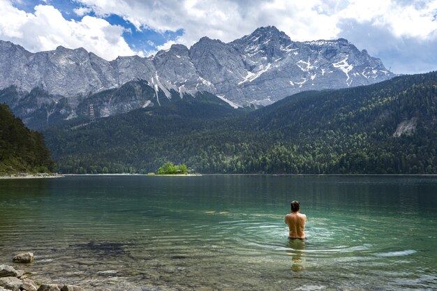 Человек купается в озере Айбзее в Германии перед горами