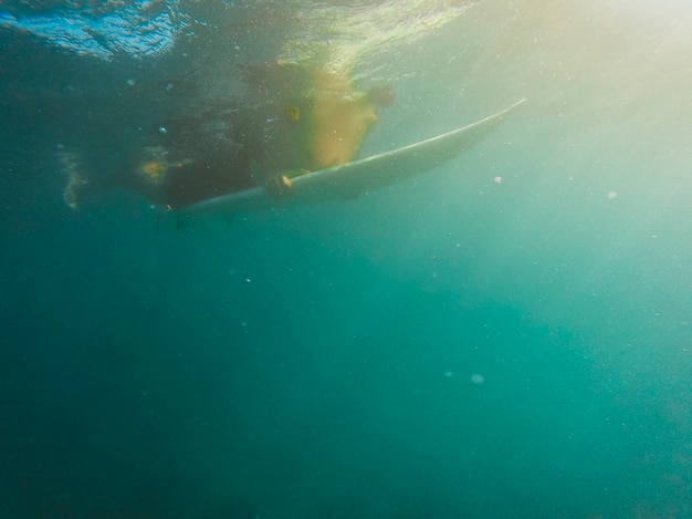 Человек плавает на доске для серфинга в океане