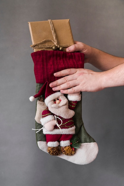 Foto gratuita persona che prende il contenitore di regalo dal calzino di natale