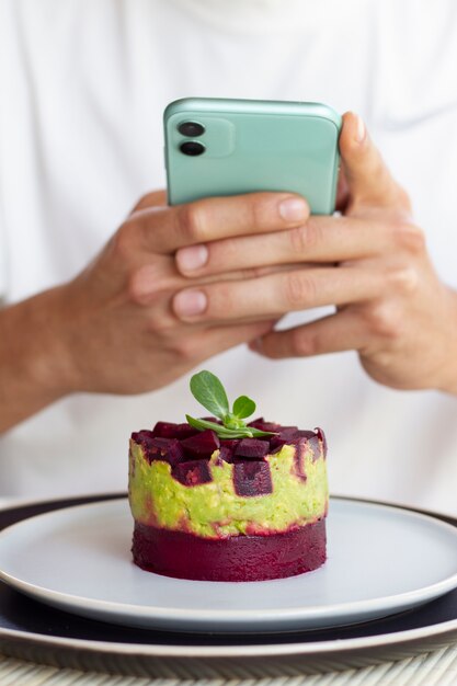 Person taking photo of fruit dessert with smartphone