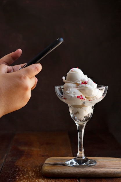 スマートフォンでガラスのアイスクリームの写真を撮る人