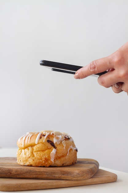 Free photo person taking photo of puff pastry with topping using their smartphone