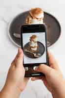 Foto gratuita persona che scatta foto con lo smartphone del dessert con cacao in polvere