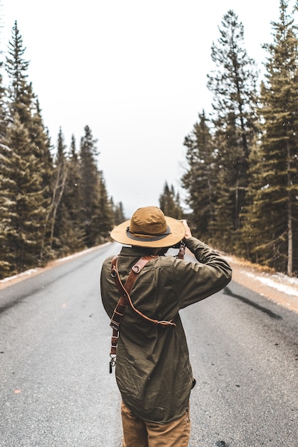 木々の間の道路の写真を撮る人