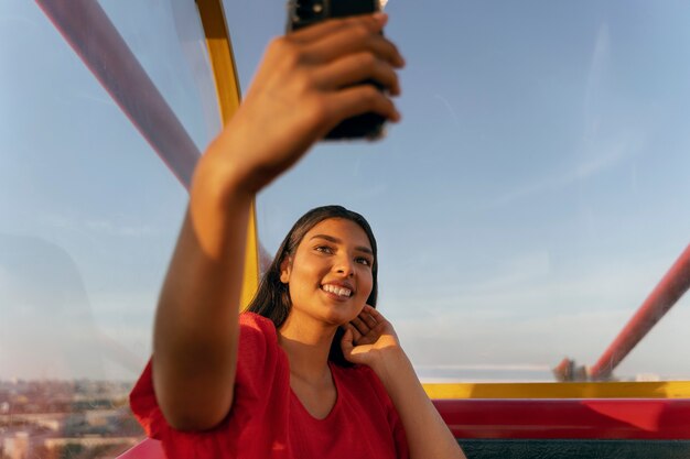 Persona che si fa selfie con lo smartphone mentre si trova sulla ruota panoramica