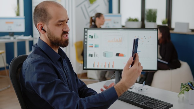 Person talking to colleagues on video call communication, using smartphone for business meeting. Businessman holding mobile phone for online conference with workmates in corporate office