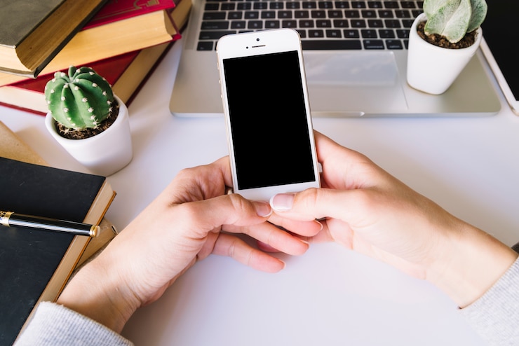 Free Photo person touching mobile phone on a desk