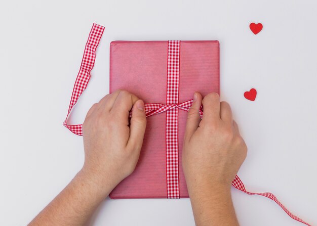 Person tying bow on pink gift box 