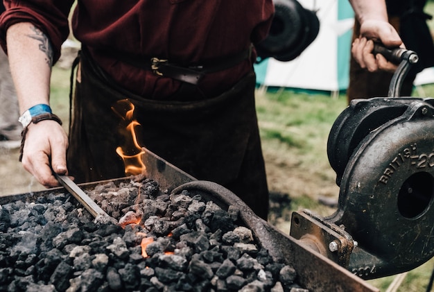 Person using hot coal with some blacksmith equipment