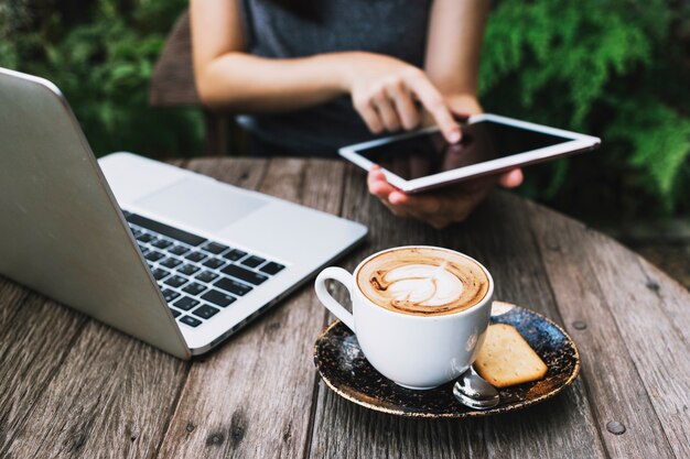 Person using tablet near laptop and coffee