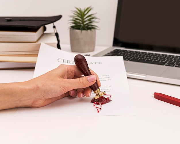 Free photo person using wax seal for graduation diploma certificate