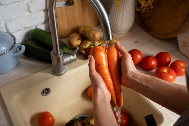 Person washing carrots in the kitchen
