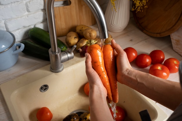 Foto gratuita persona che lava le carote in cucina