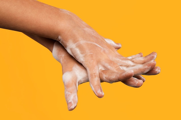 Person washing hands isolated on orange