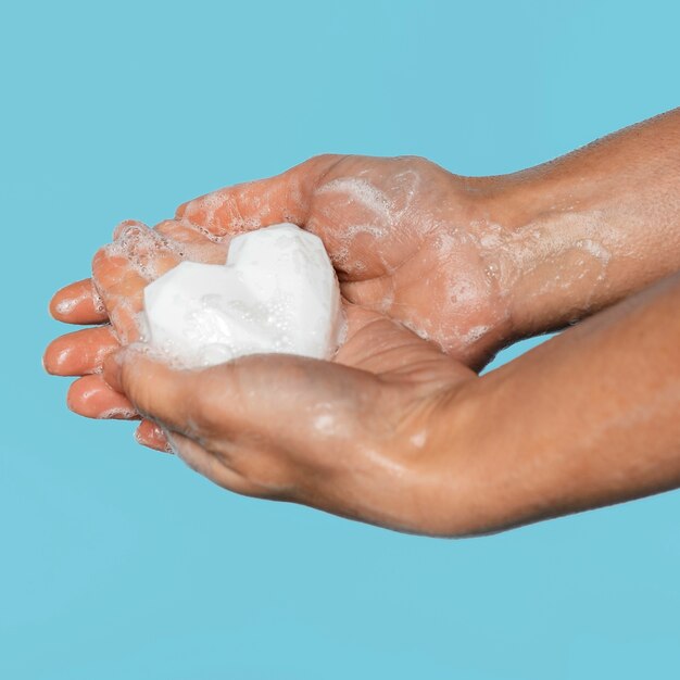 Person washing hands with a heart shaped white soap