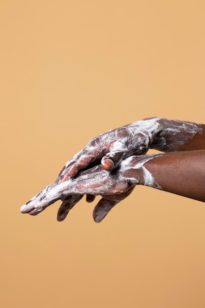 Person washing hands with soap isolated on orange