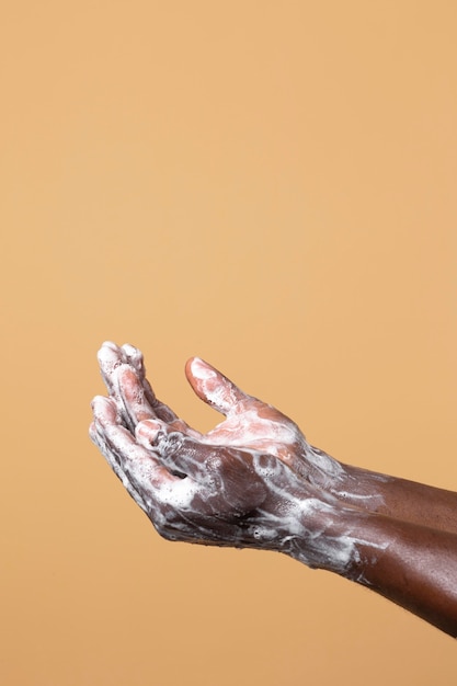 Person washing hands with soap isolated on orange