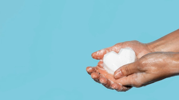 Person washing hands with a white soap with copy space